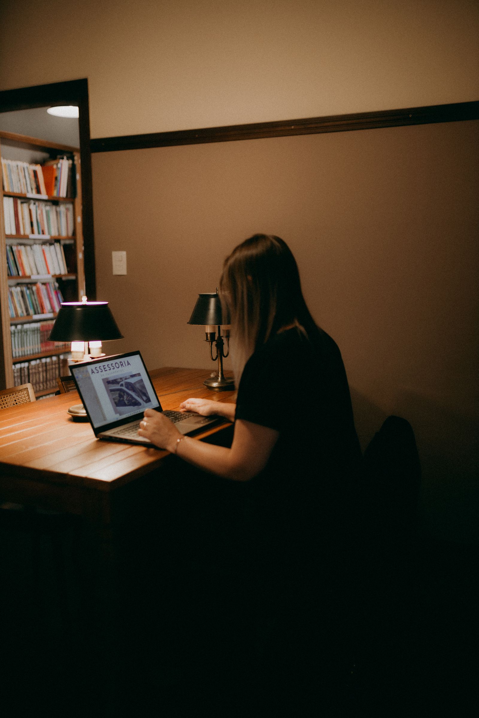 A person working on a laptop in a dimly lit home study
