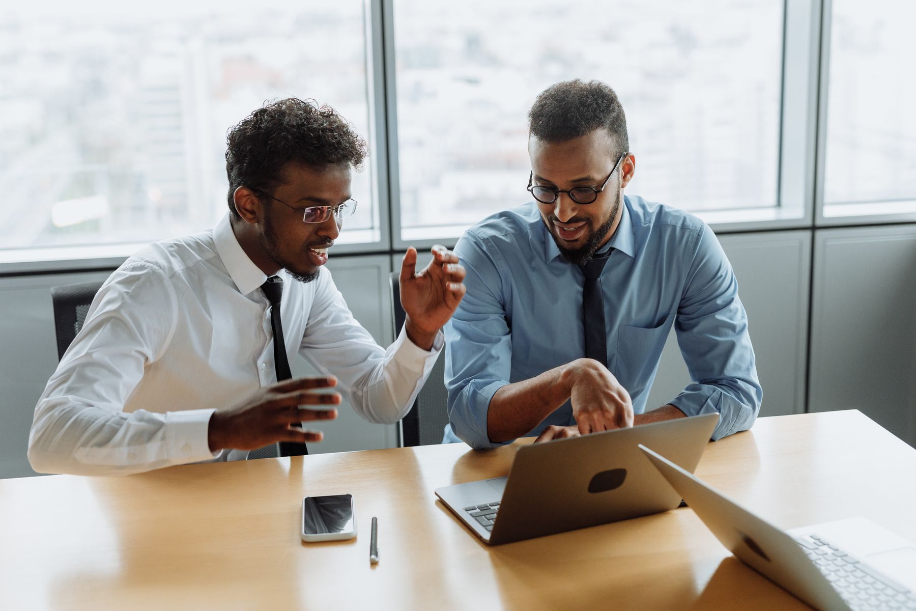 Two professionals in an open, friendly conversation over a laptop